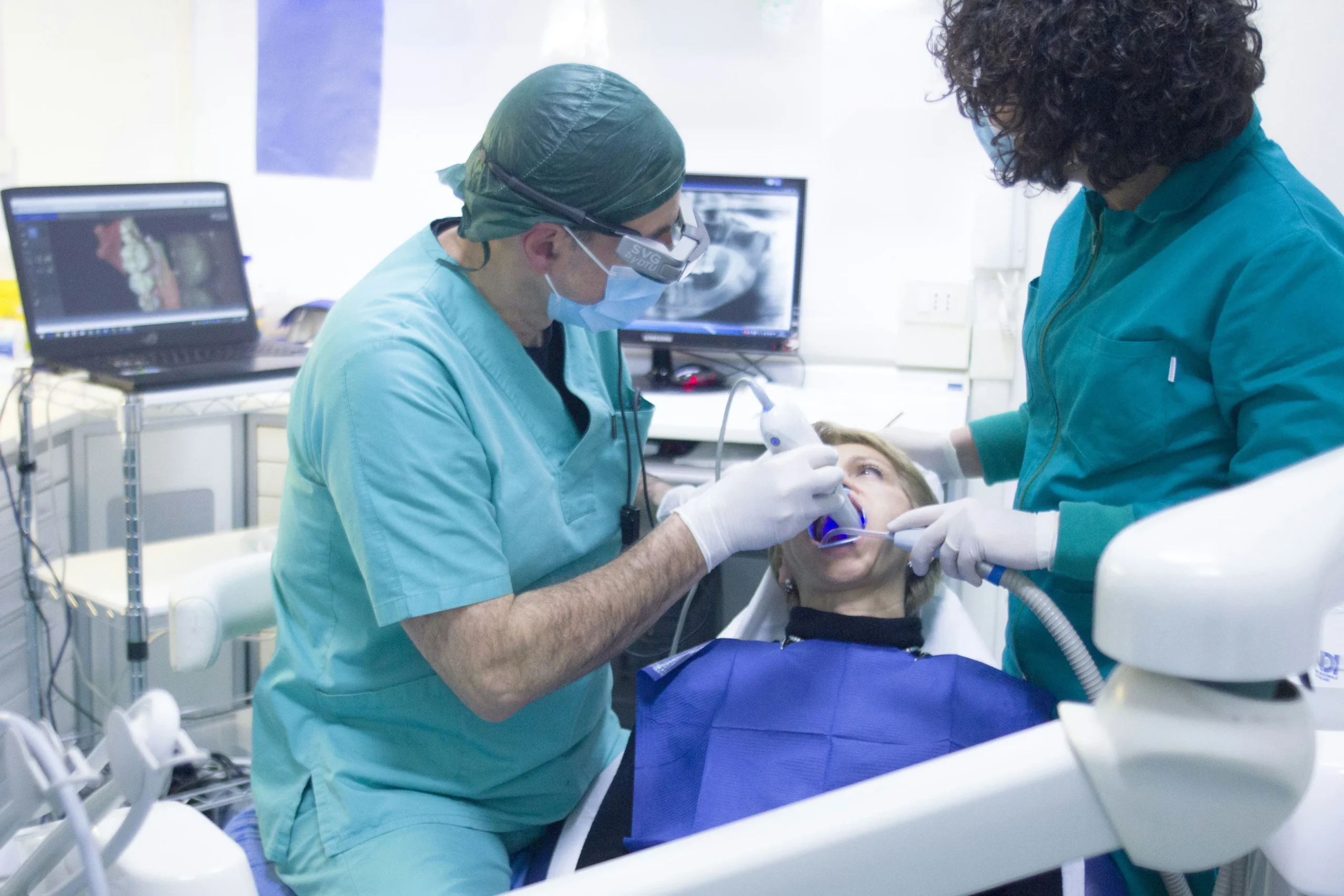 Dentist performing a dental procedure on a patient with a dental assistant assisting